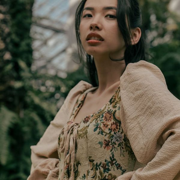 A serene individual smiling lightly, with a backdrop of soft green light suggesting well-being.