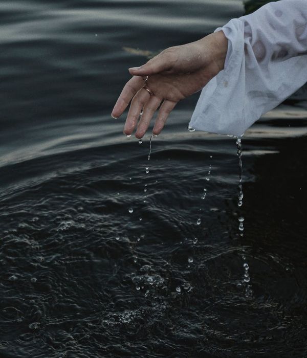 Woman performing a gentle, fluid movement in a bright, minimalist room.